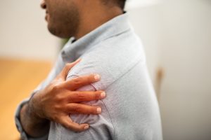 Man who experienced orthopaedic negligence holding shoulder.