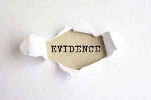 the word Evidence appearing behind torn white paper, gray background.