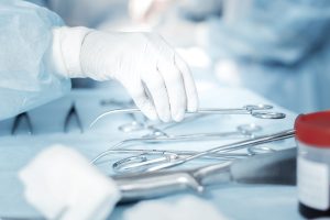 Gloved hands picking up surgical instruments. 