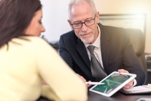 A solicitor going through an NHS compensation payouts guide with his client during a meeting