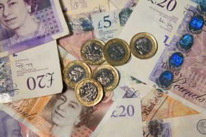 An overhead view of pound coins on top of several banknotes.